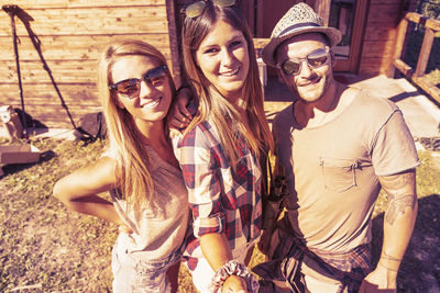 Portrait of smiling friends standing against trees