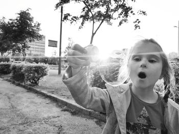 Portrait of girl holding plants against sky