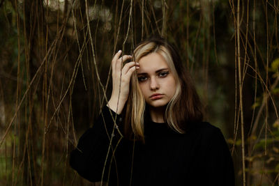 Portrait of beautiful young woman standing against plants outdoors