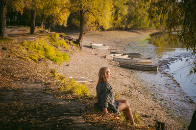 Young woman sitting by lake in forest