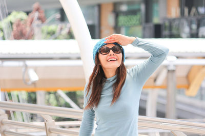 Woman shielding eyes while standing on covered bridge