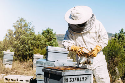 Beekeeper holding equipment while working