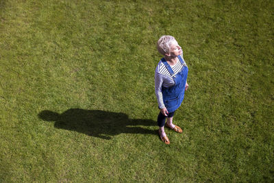 Contented woman standing on grass in garden during sunny day