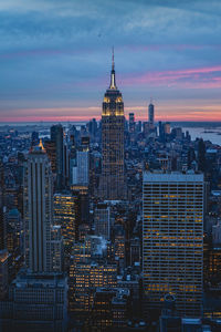 Illuminated buildings in city against sky during sunset