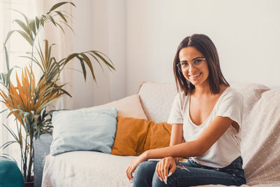 Happy woman sitting on sofa at home