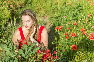 Close-up of young woman by poppy flowers