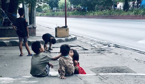 People sitting on sidewalk in city