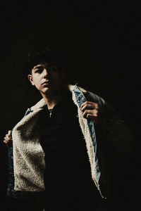 Young man looking away against black background