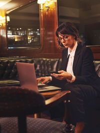 Woman using mobile phone while sitting in office