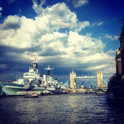 Boats at harbor against cloudy sky