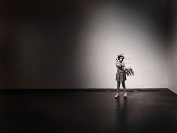 Side view of boy standing on table against wall