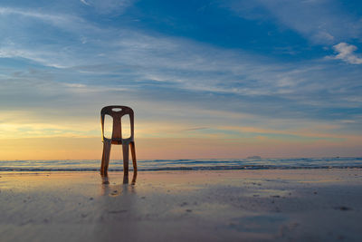 Lifeguard hut on beach against sky during sunset