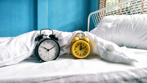 Close-up of alarm clocks on bed at home