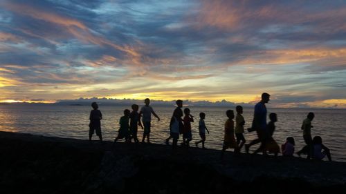 Silhouette of people at beach during sunset