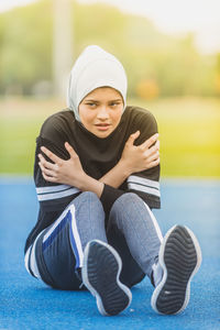 Thoughtful female athlete sitting at stadium