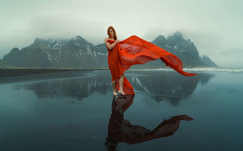 Rear view of woman with arms raised against sky