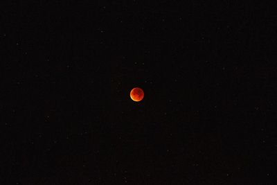 Low angle view of red moon against sky at night