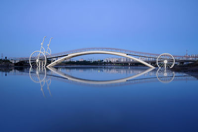 Arch bridge over lake against clear blue sky