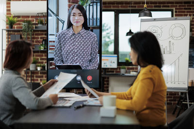 Side view of young woman using digital tablet while sitting at office