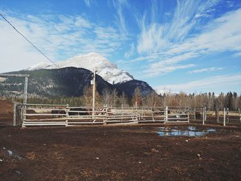 Built structure on field by snowcapped mountain against sky