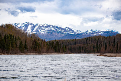 Scenic view of lake by snowcapped mountains against sky