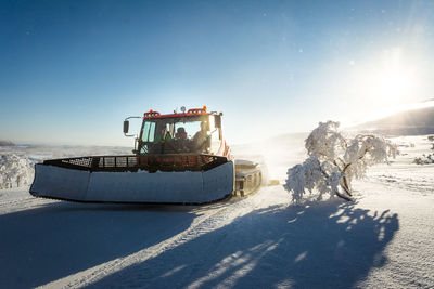 Construction machinery on snow field against blue sky