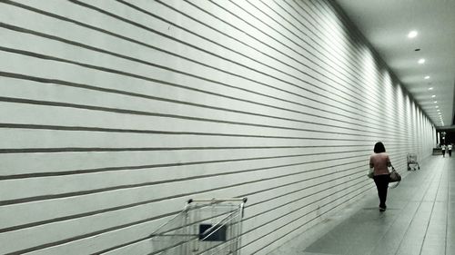 Rear view of woman walking by wall at supermarket