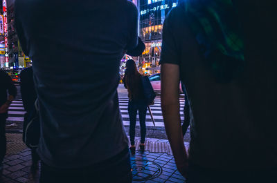 Rear view of people standing on street at night