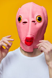 Portrait of woman with mask against yellow background