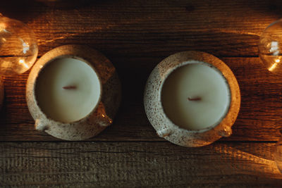 Natural candles in clay coasters on a wooden table