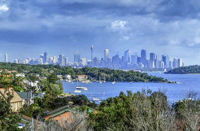 City at waterfront against cloudy sky