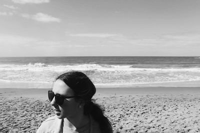 Young woman standing on beach against sky