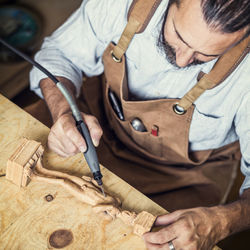 Carpenter carving on figurine in workshop