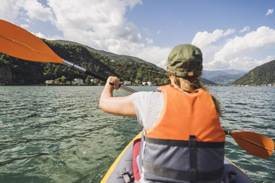 Woman wearing life jacket kayaking at lake