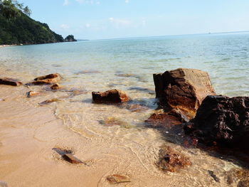 Rock formation on beach against sky