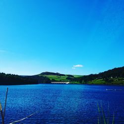 Calm lake against clear blue sky