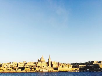 River in front of cityscape against clear blue sky