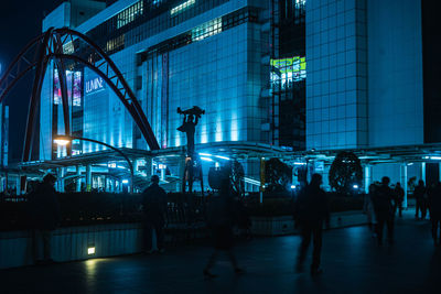 Group of people walking in illuminated building at night