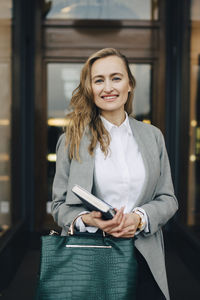 Portrait of a smiling young woman holding camera