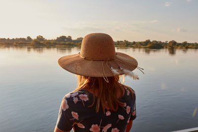 Woman with a big hat watching the sunset at the okavango river