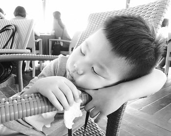 Boy holding flat bread while sleeping on chair at restaurant