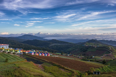 Scenic view of field by mountains against sky