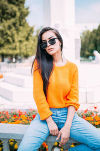 Young woman wearing sunglasses sitting outdoors