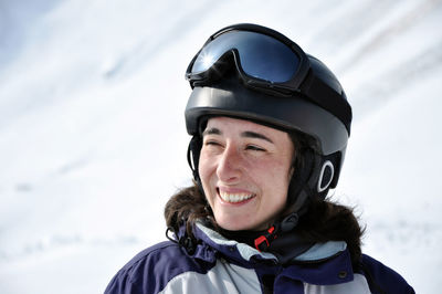 Close-up of cheerful female skier wearing helmet on sunny day