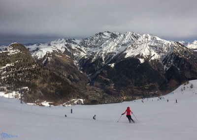 People skiing against snowcapped mountainn against sky
