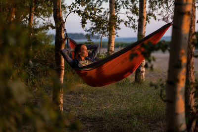 Woman in a hammock in nature is enjoying nature and the sunset