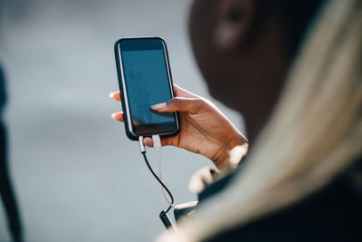 Cropped image of teenage girl listening music through smart phone