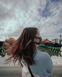 Rear view of woman wearing mask while standing in city