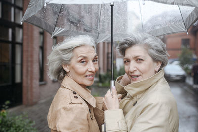 Female friends holding umbrella during rainy day