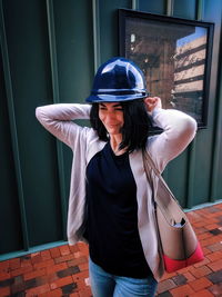 Young woman wearing hardhat against built structure